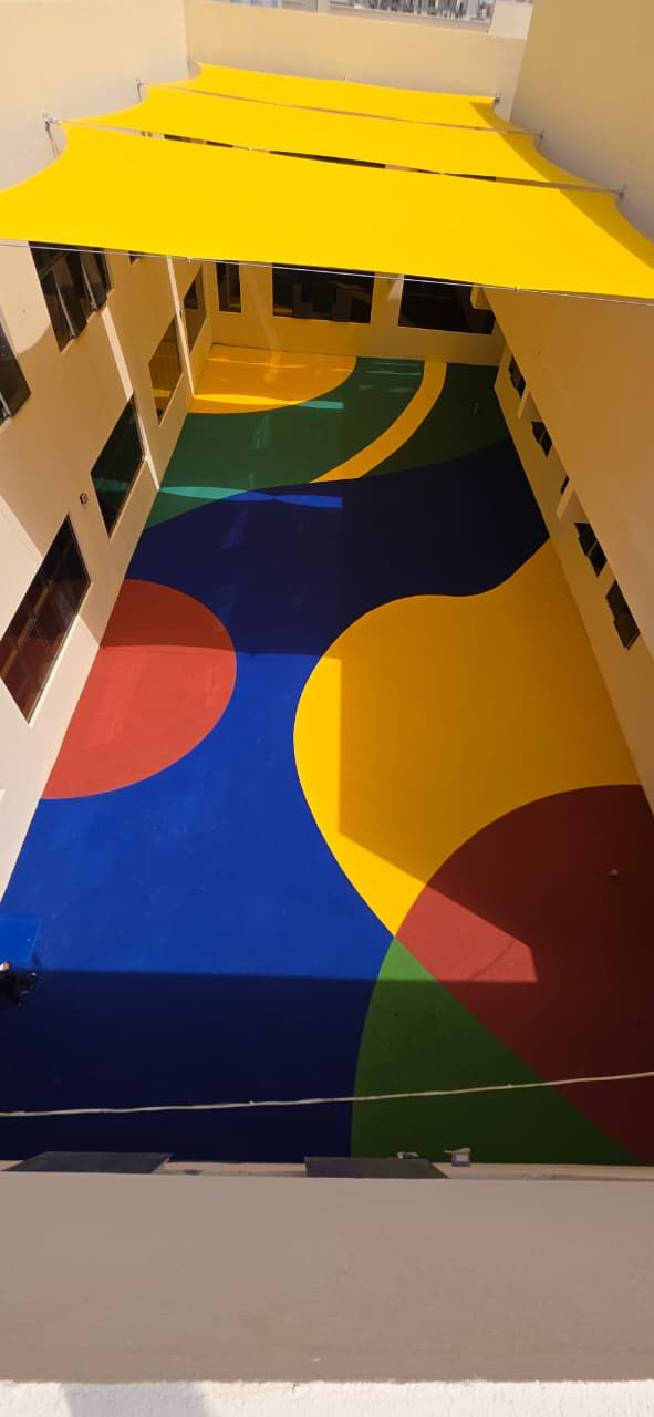 Courtyard play deck in bold colour blocks under yellow shade sails