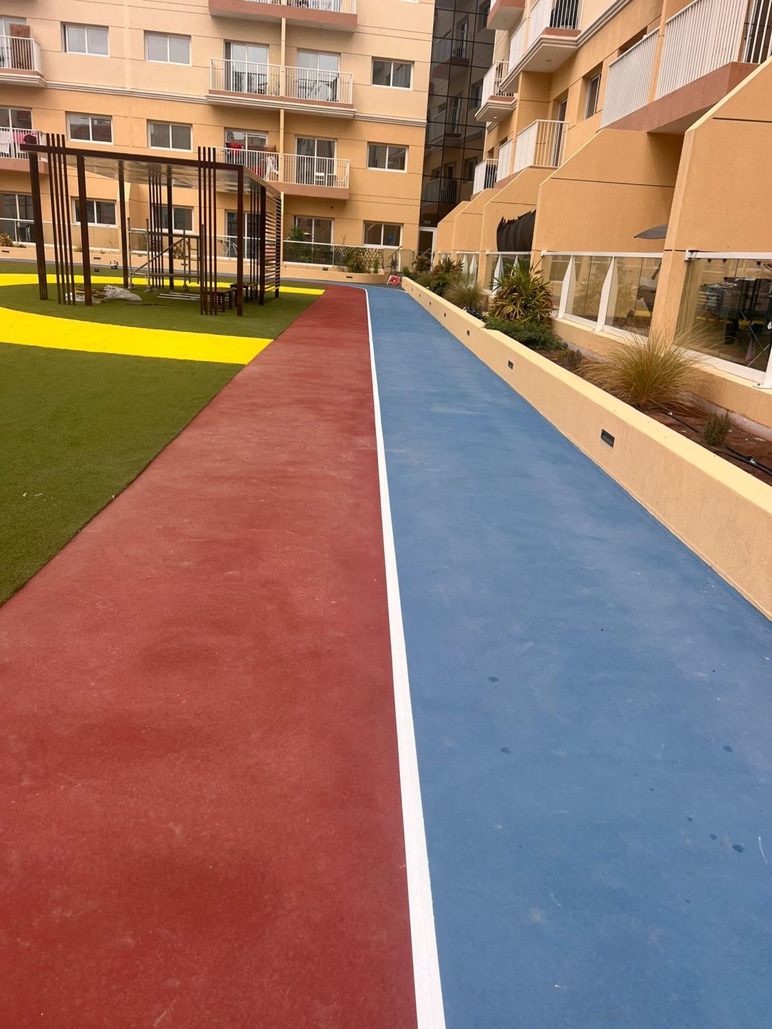 Red and blue running track laid through a residential courtyard