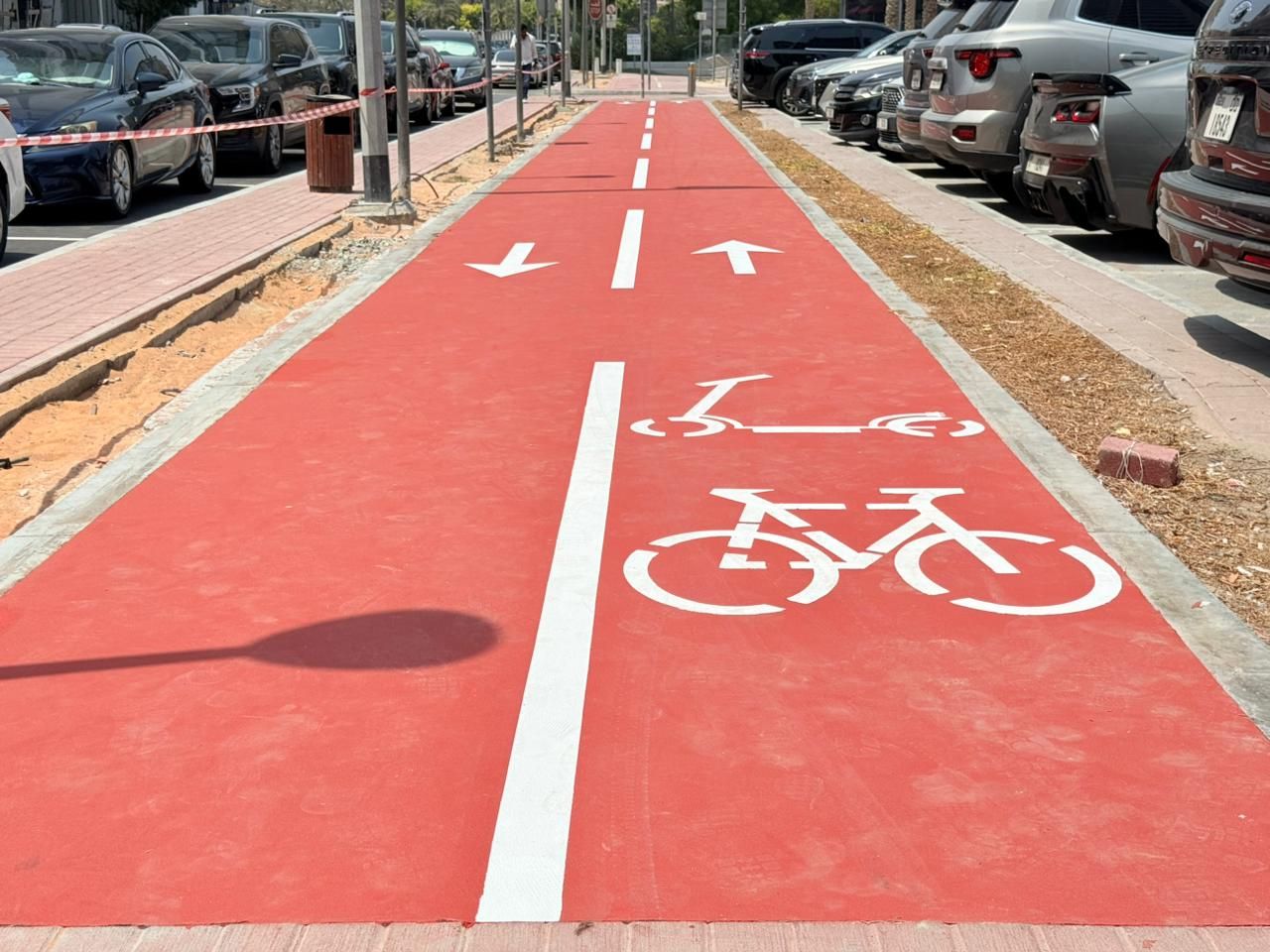 Red cycle and scooter track with directional arrows and lane marking
