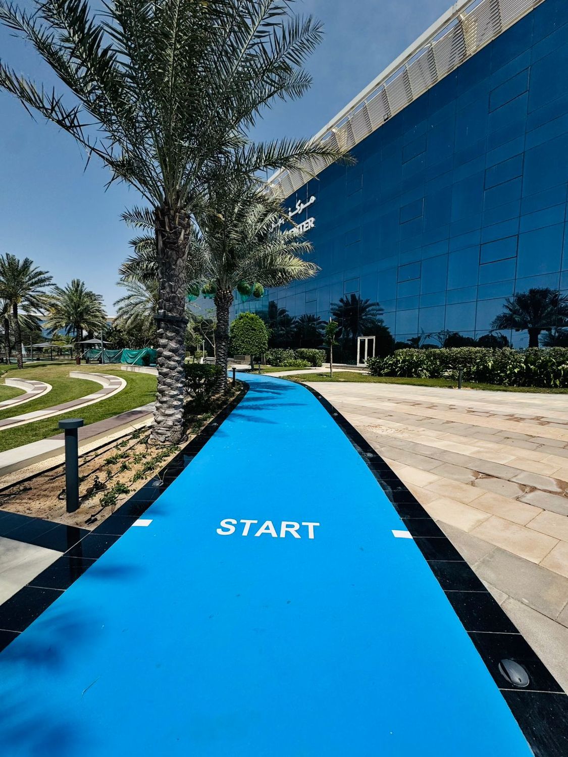 Blue jogging track running through landscaped grounds