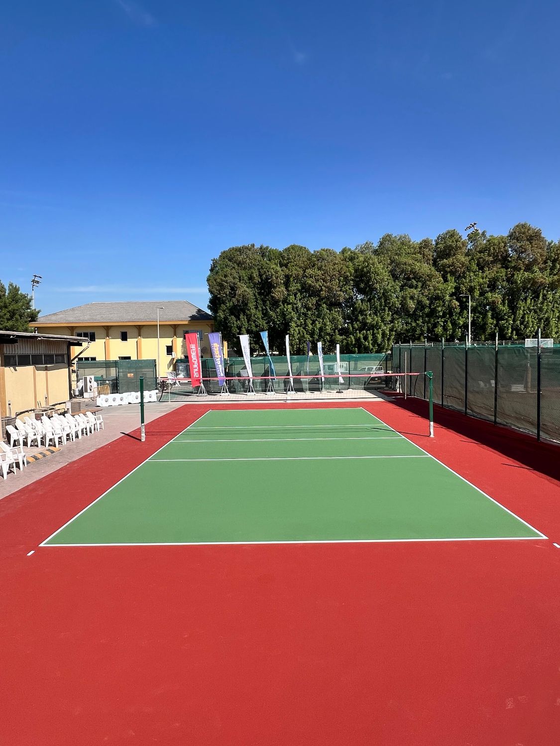 Outdoor acrylic tennis court in green and red with net and line marking