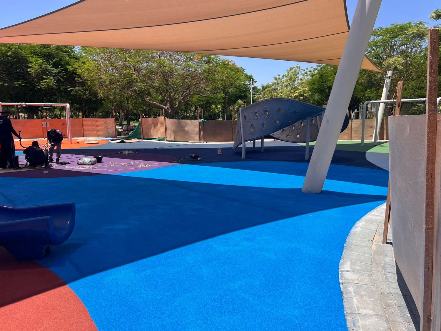 Poured rubber playground surfacing in blue and purple around play equipment