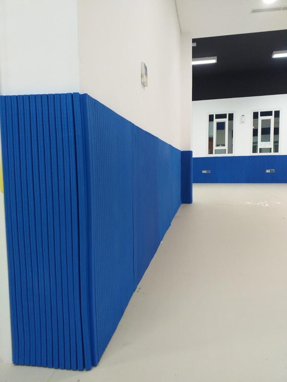 Blue protective padding fitted to walls and columns