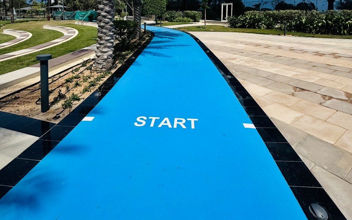 Blue outdoor jogging track with START marking running through landscaped grounds